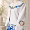 Detalle de chaqueta blanca Amalfi con bordado de limones y aves.